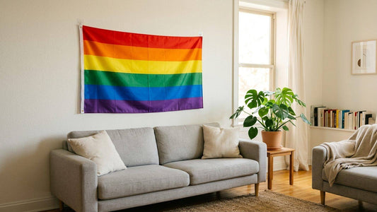 Rainbow Pride flag hung with clear removable hooks above a sofa in a bright apartment